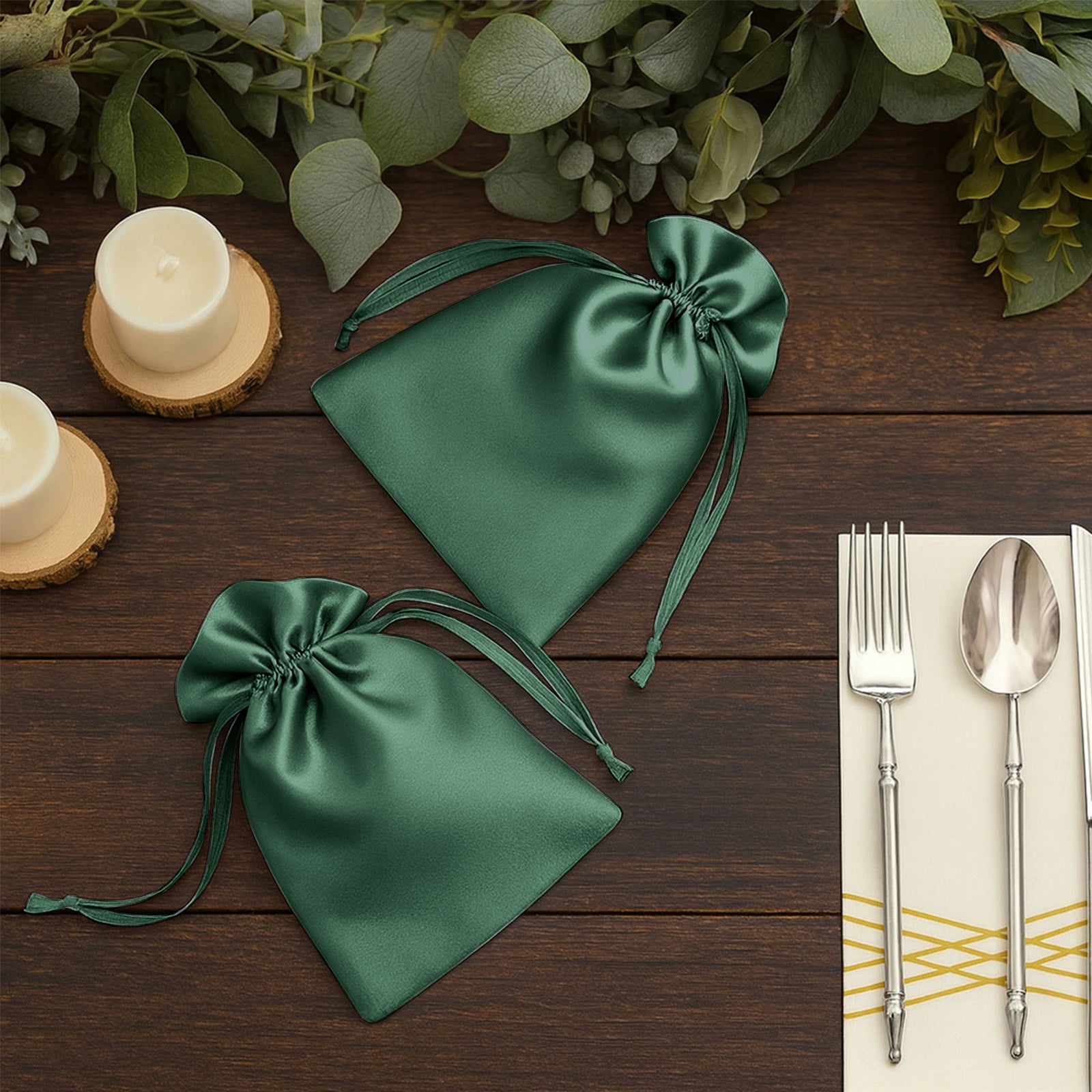 Hunter emerald green satin drawstring wedding favor bags on a wooden table.