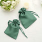 Hunter emerald green satin drawstring gift bags on a table with flowers.
