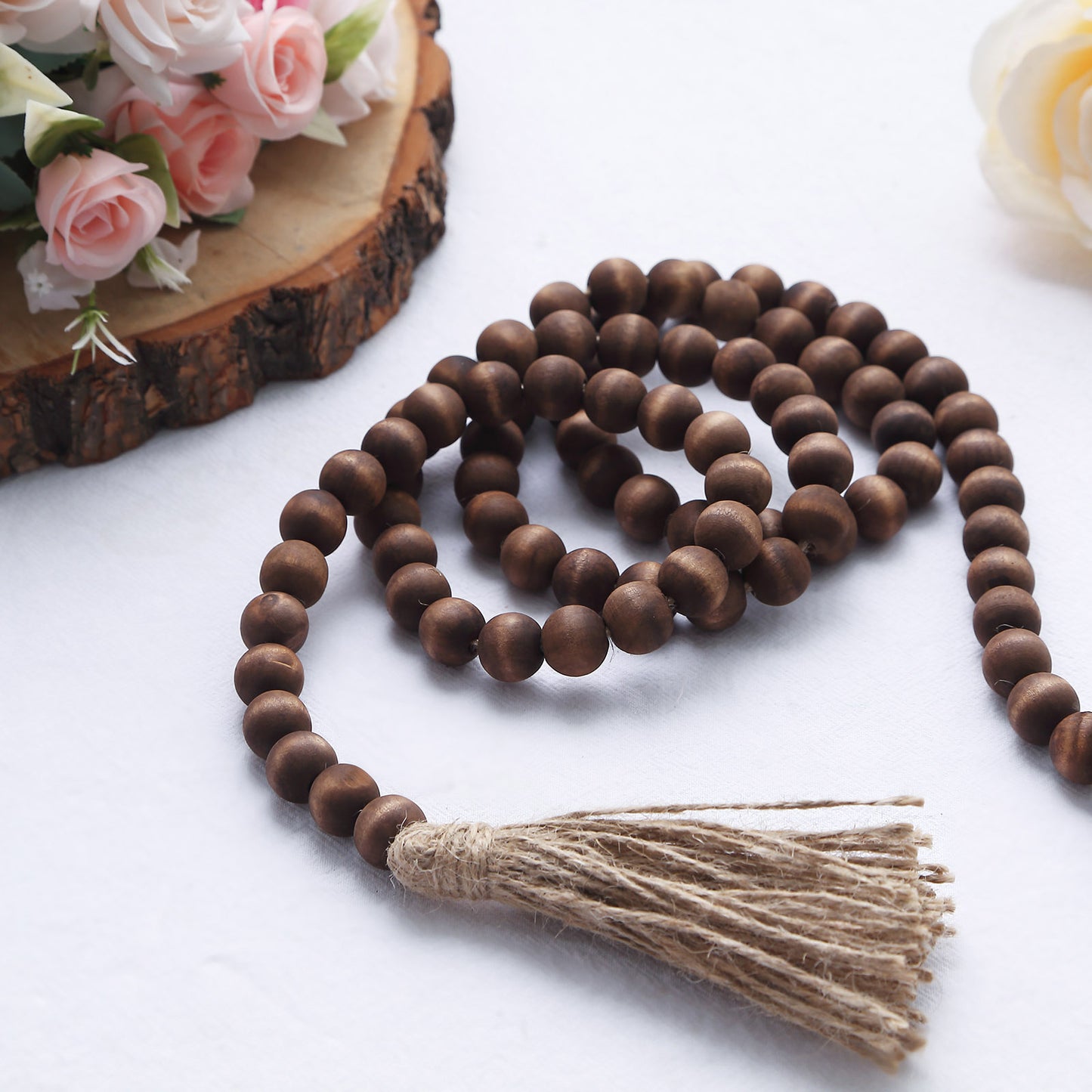 Brown rustic wood bead garland with tassels on a white background.