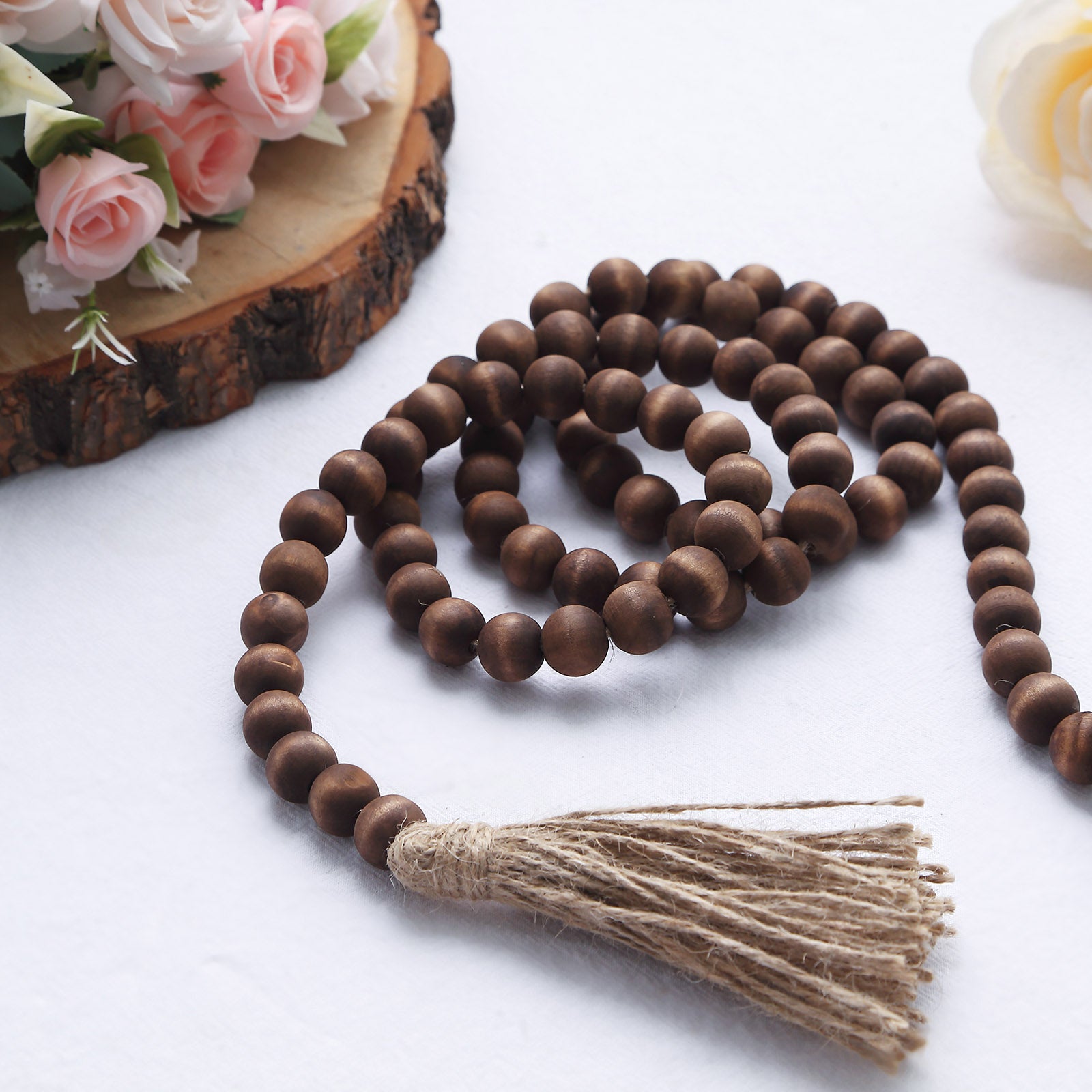 Brown rustic wood bead garland with tassels on a white background.