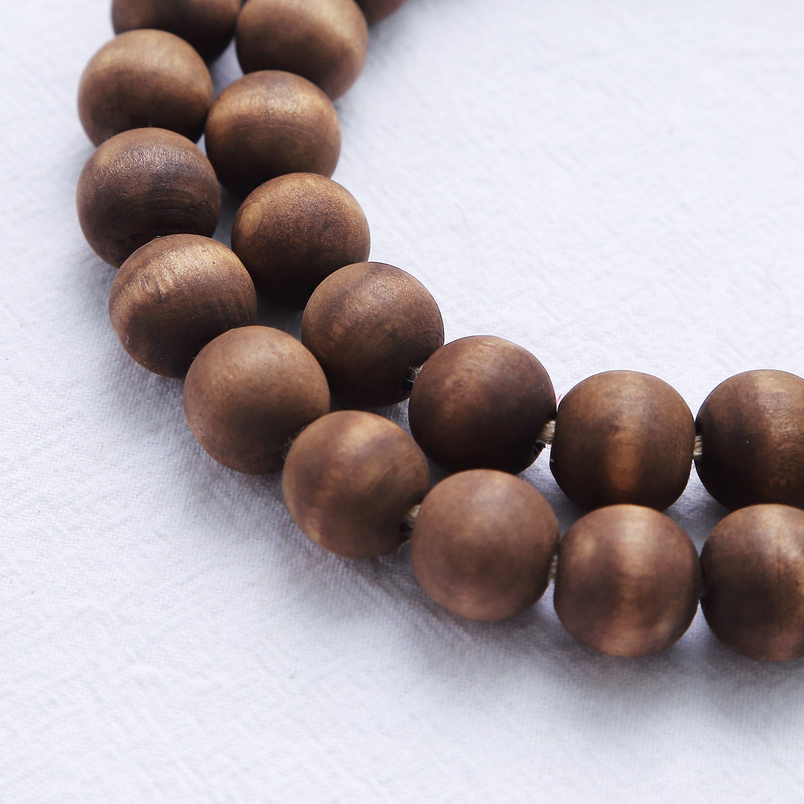 Brown rustic wood bead garland with tassels for farmhouse decor.