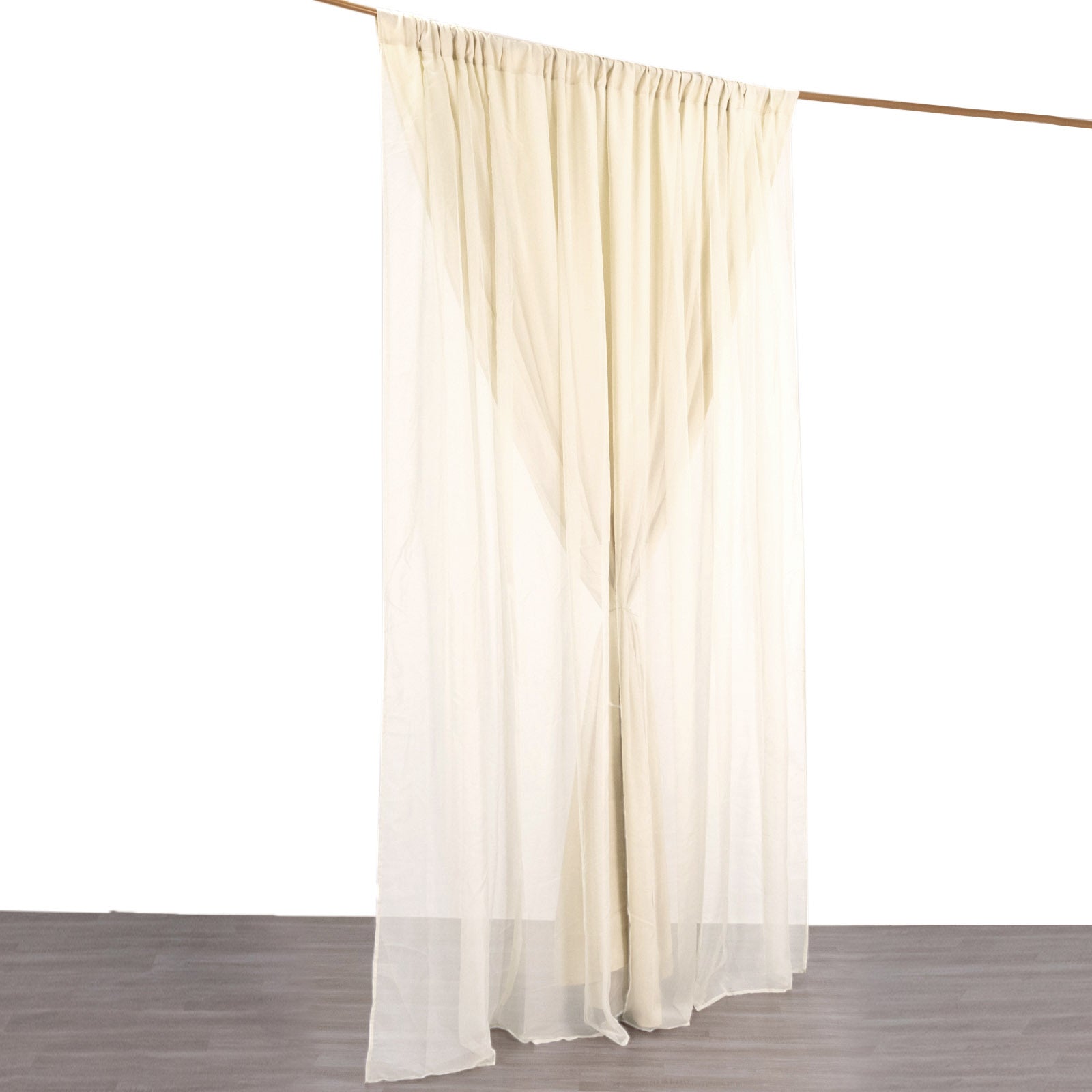 Beige chiffon curtain drapes hanging from a rod.