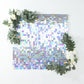 Iridescent blue sequin shimmer wall backdrop with floral accents.
