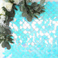 Iridescent blue sequin backdrop with mermaid scales pattern and greenery.