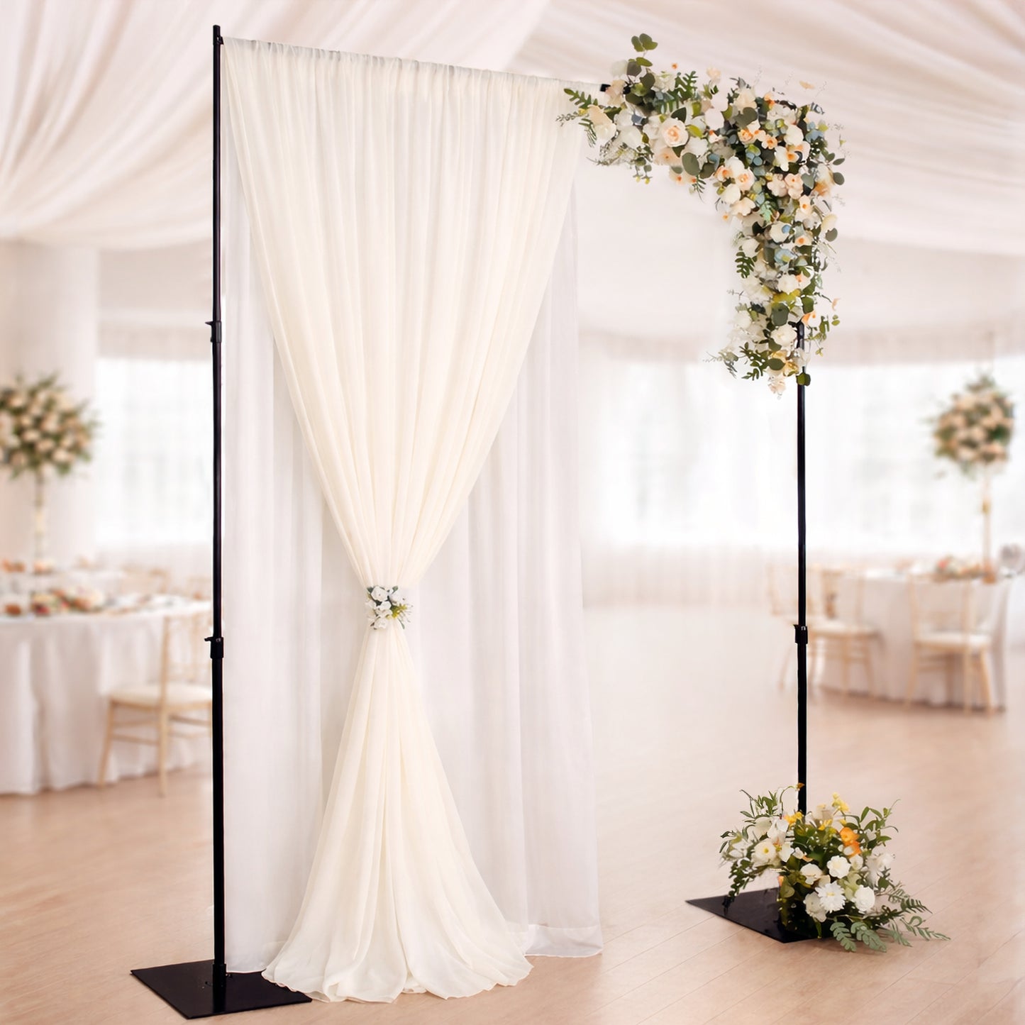 Black heavy duty metal backdrop stand with drapery and floral arrangement.