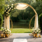 Gold metal arch frame with floral arrangement and draped fabric backdrop.