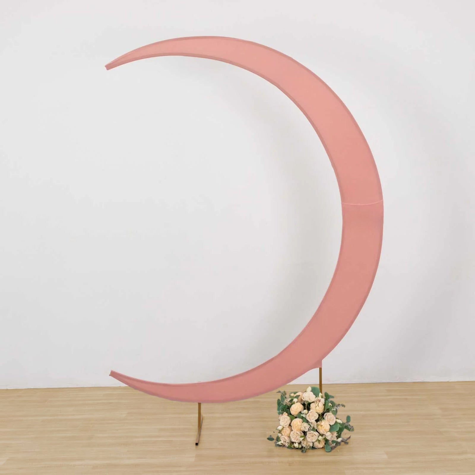 Dusty rose crescent moon wedding arch cover with floral arrangement.