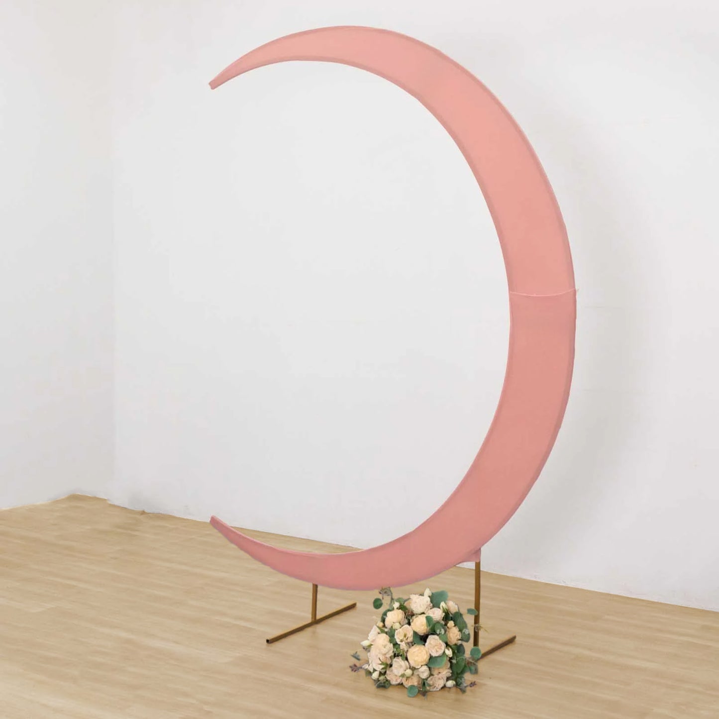 Dusty rose spandex crescent moon wedding arch cover with floral arrangement.