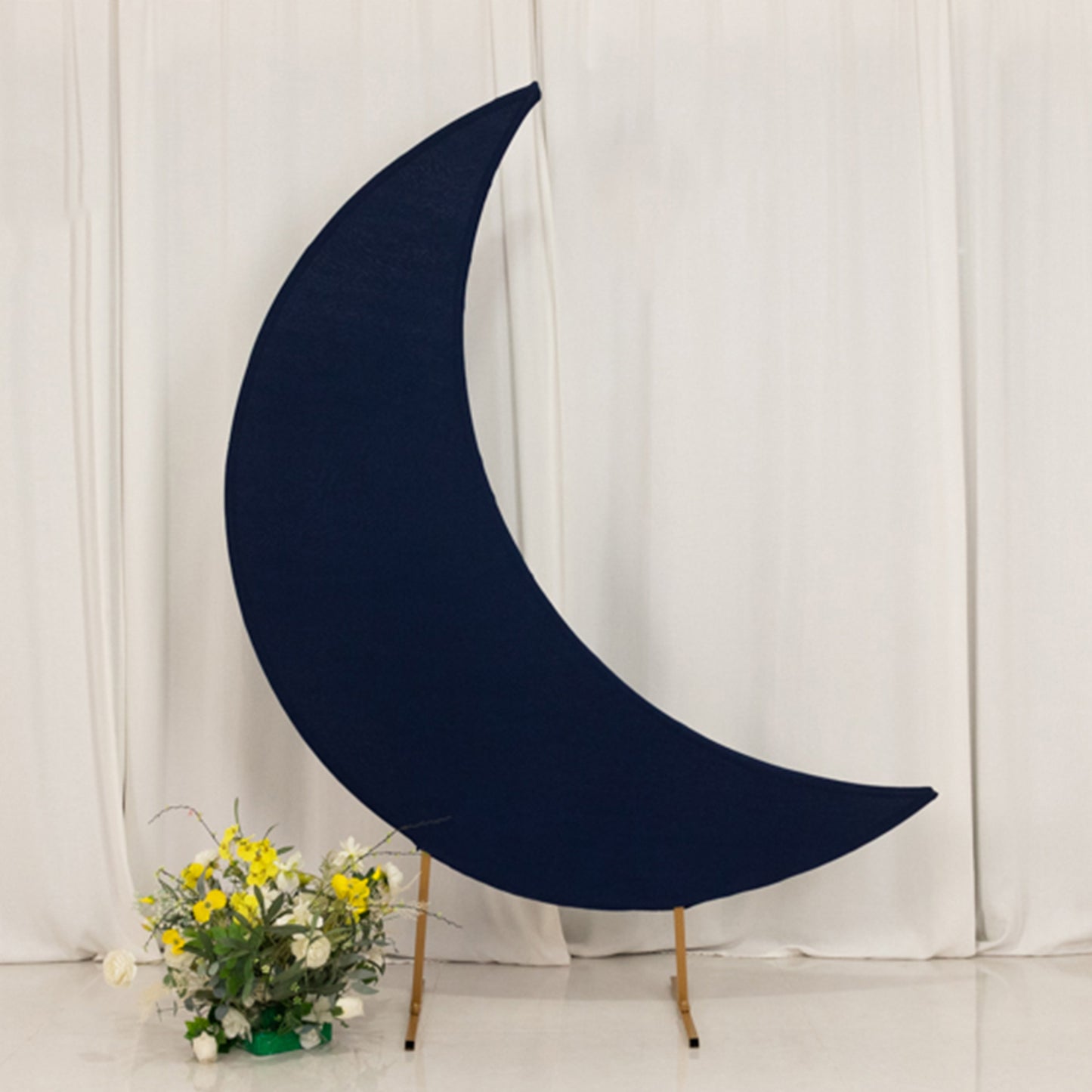 Navy blue crescent moon backdrop stand with floral arrangement.