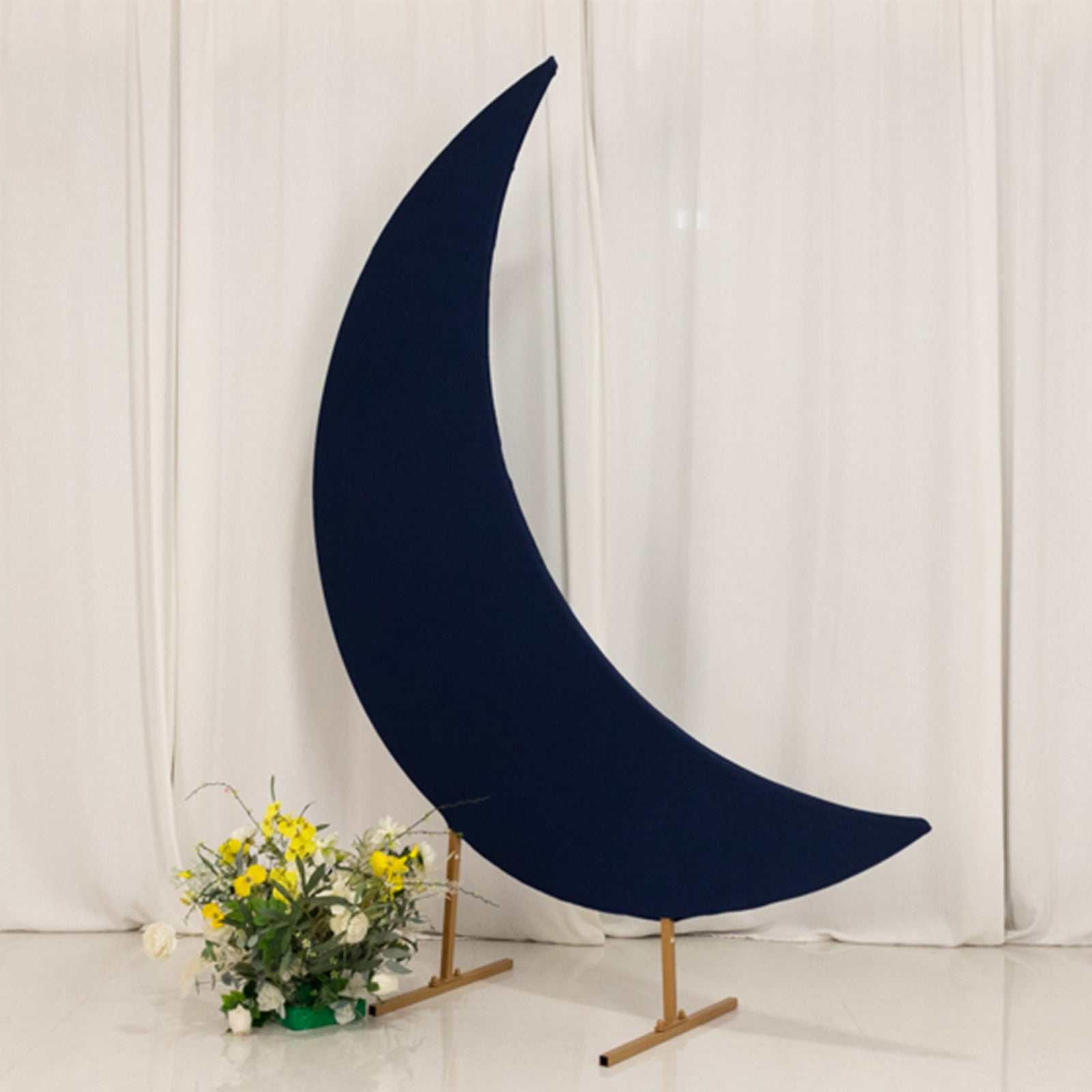 Navy blue spandex crescent moon backdrop stand with floral arrangement.