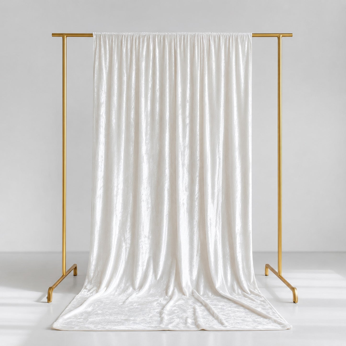White crushed velvet backdrop curtain on a gold stand.