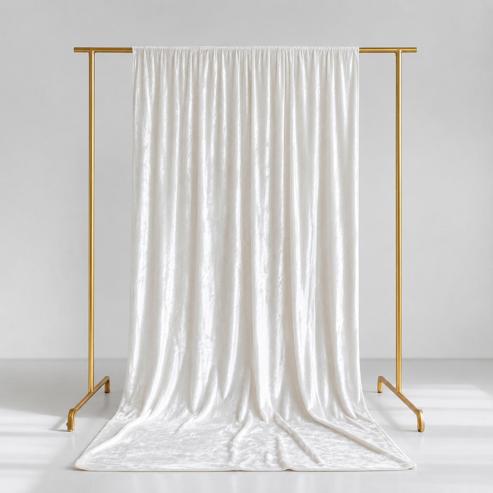 White crushed velvet backdrop curtain on a gold stand.