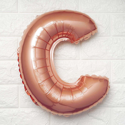 Rose gold letter balloon "C" against a white background.