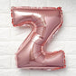 Rose gold matte letter balloon "Z" against a white wall.