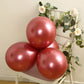 Chrome pink biodegradable latex balloons arranged on a chair.