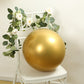 Chrome gold biodegradable latex balloon on a chair with greenery and flowers.