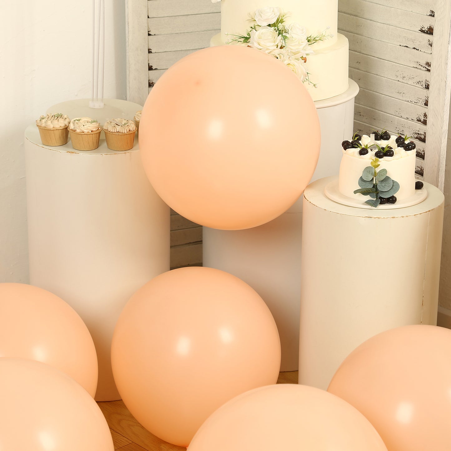 peach biodegradable balloons on display with white cakes and cupcakes