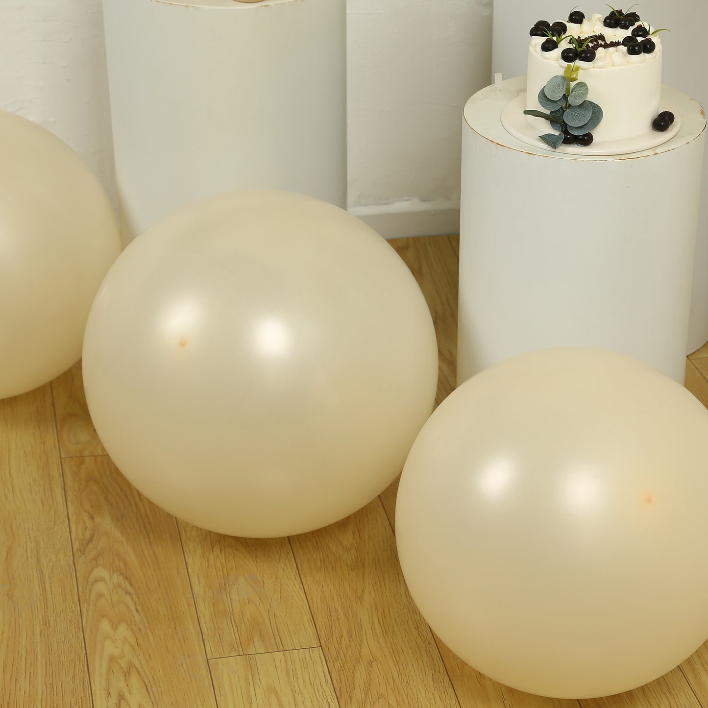 Matte pastel cream biodegradable balloons on a wooden floor.