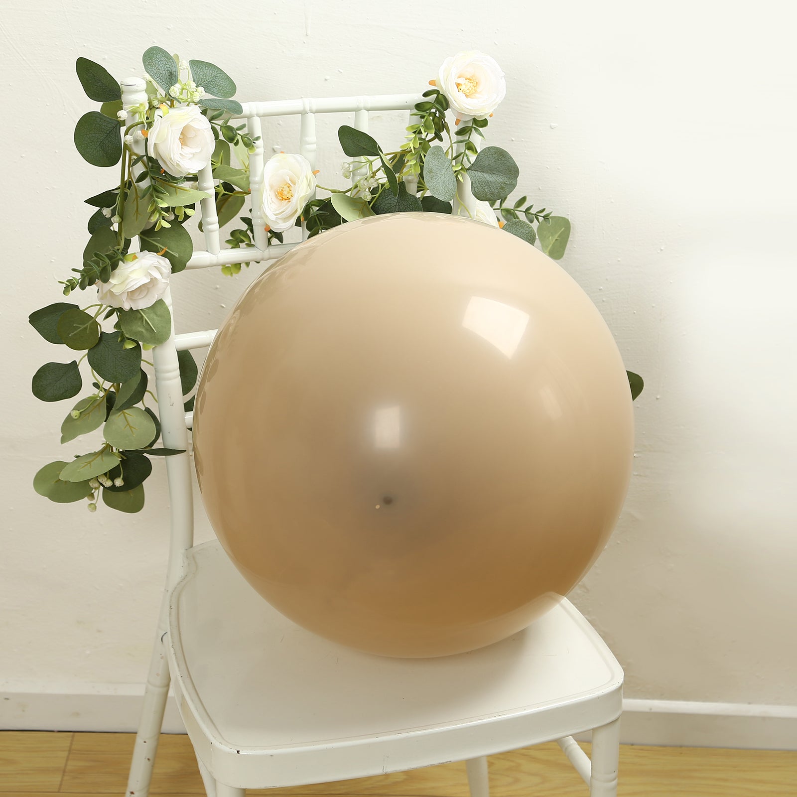 Matte pastel taupe biodegradable balloon on a chair with greenery.