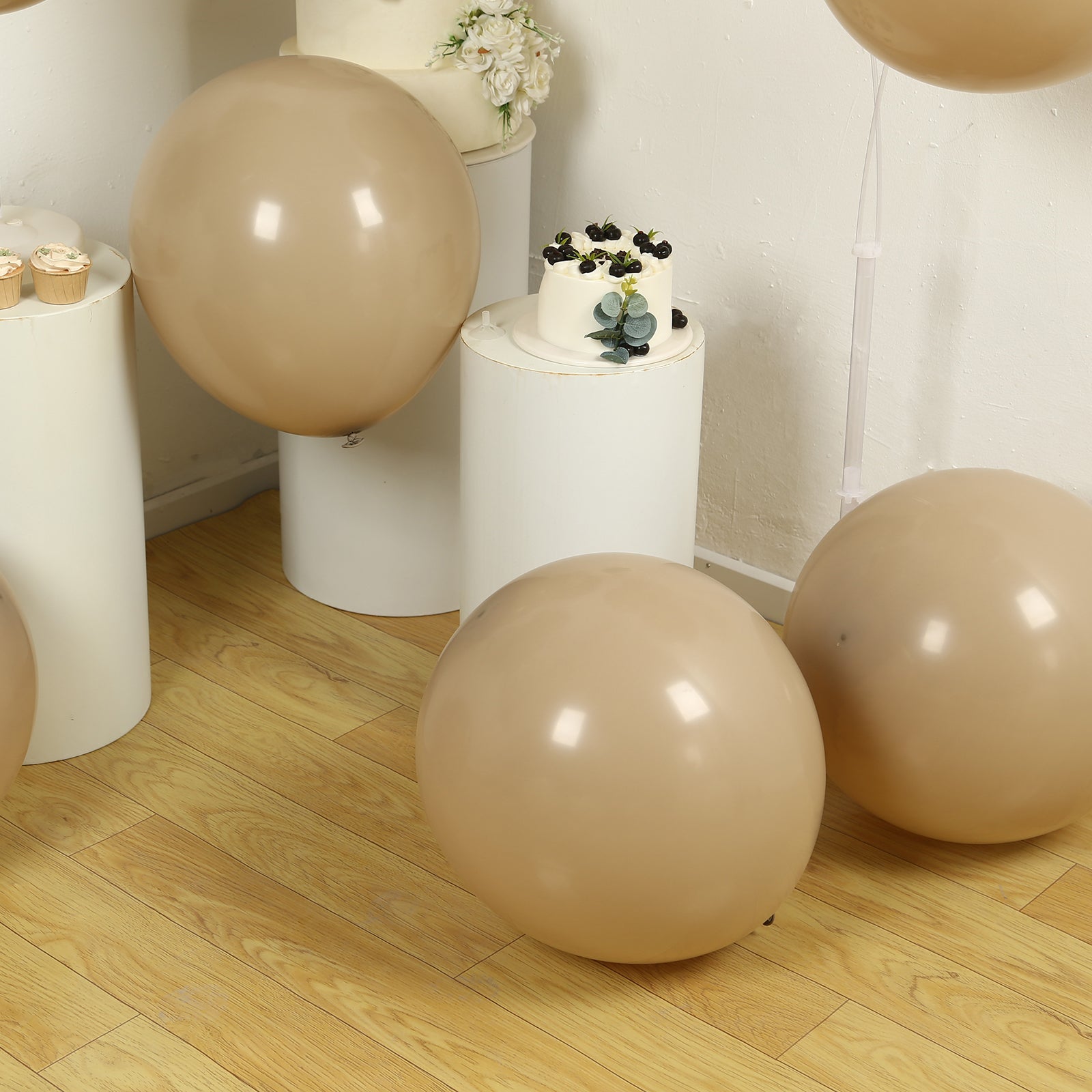 Matte pastel taupe biodegradable balloons on a wooden floor.