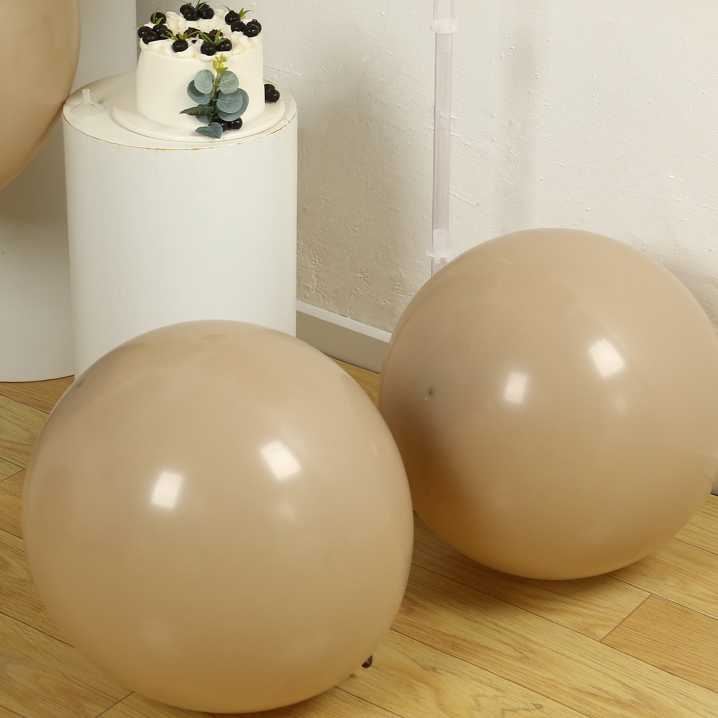 Matte pastel taupe biodegradable balloons on a wooden floor.