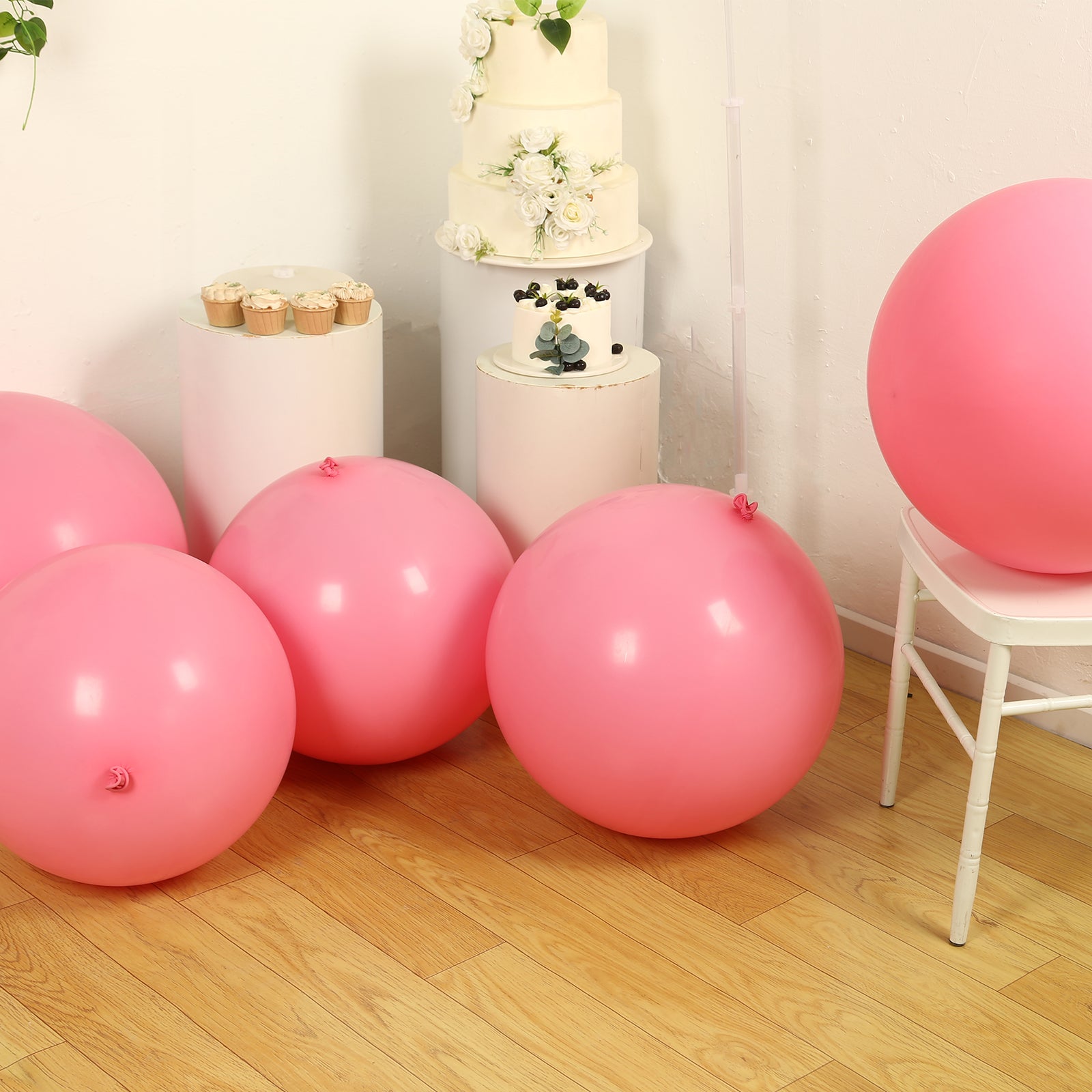 Large matte pastel pink biodegradable balloons on a wooden floor.