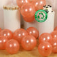 Rose gold biodegradable balloons scattered on the floor at a party.