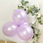 Lavender lilac biodegradable balloons on a chair with greenery and flowers.