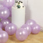 Lavender biodegradable balloons around a white cake on a wooden floor.