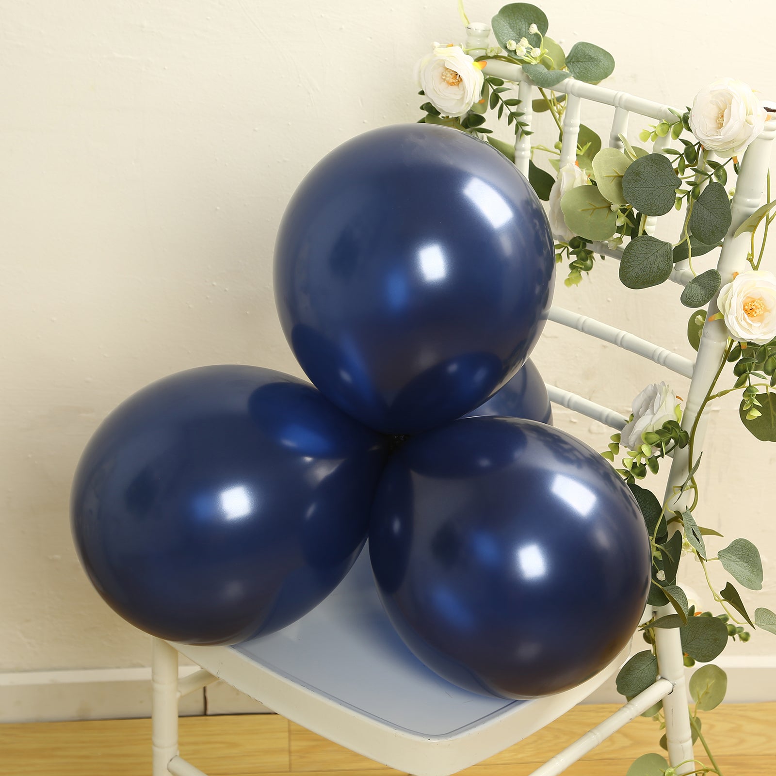 Navy blue biodegradable balloons arranged on a chair with greenery.