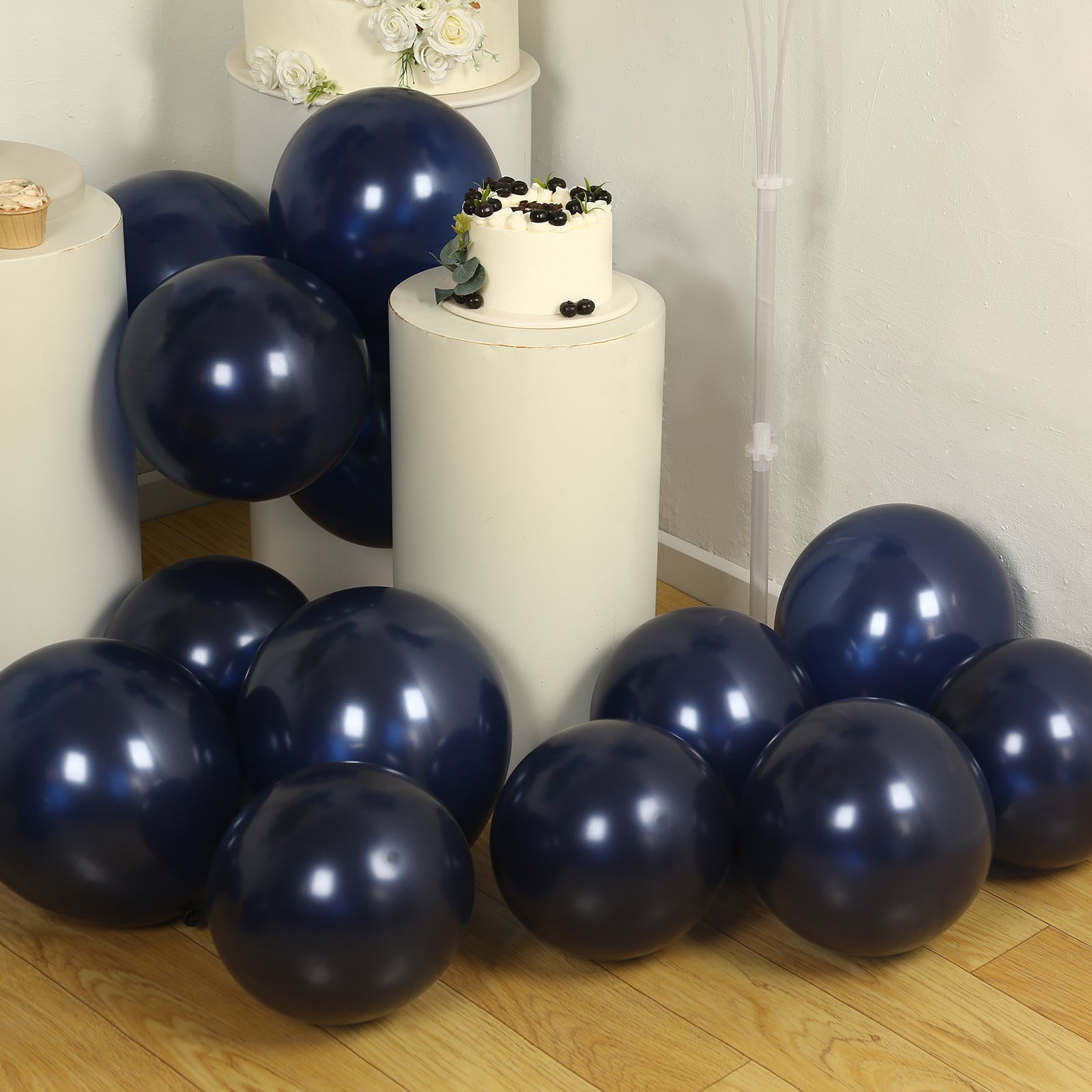 Navy blue biodegradable balloons scattered on the floor beside a cake.