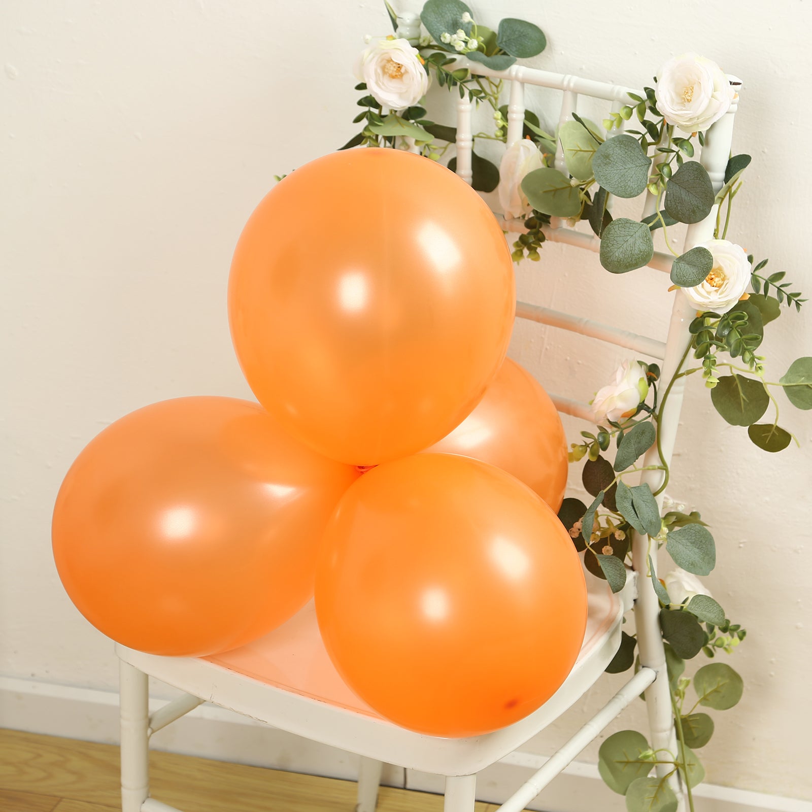 Orange biodegradable balloons on a chair with greenery.