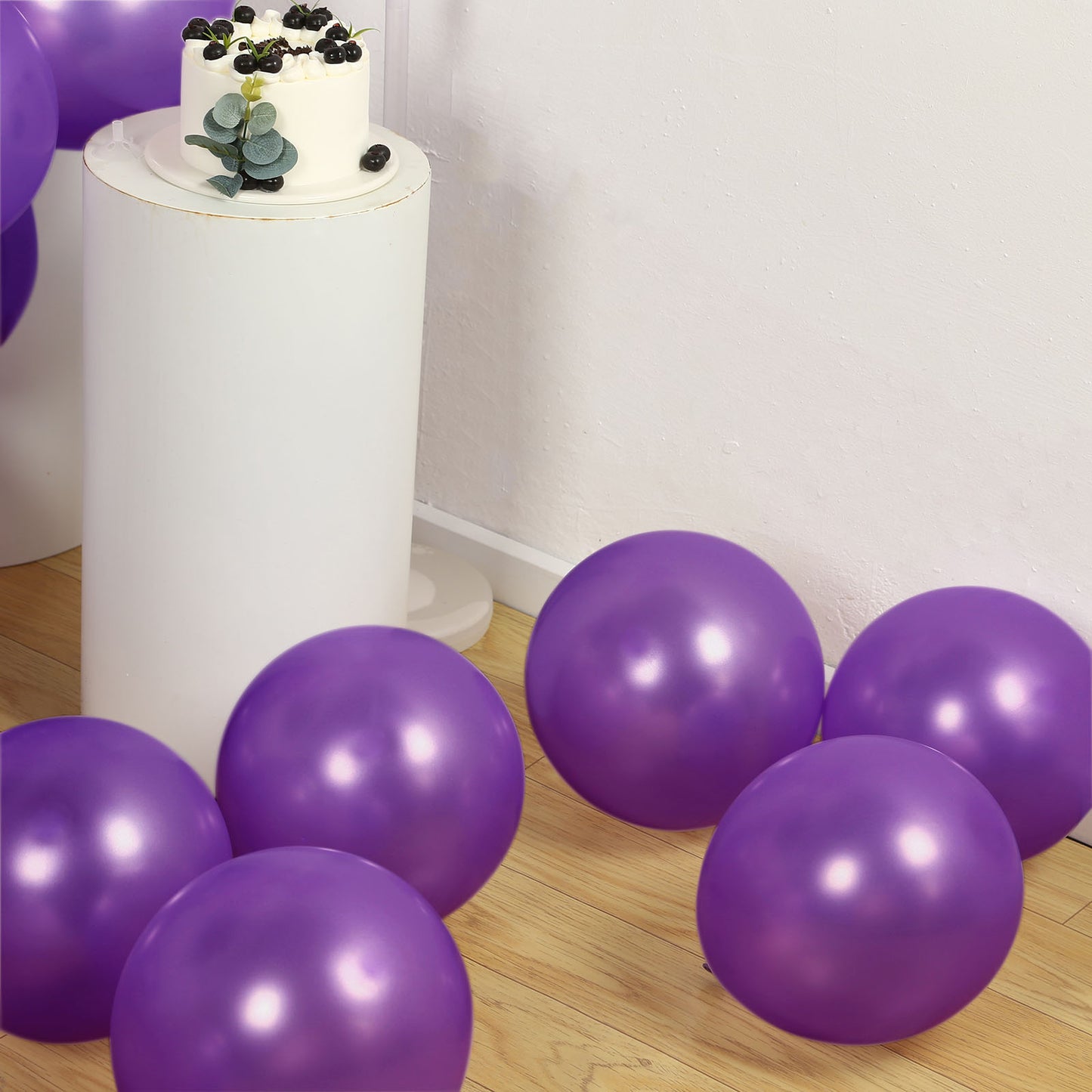 Purple biodegradable balloons on a wooden floor with a cake in the background.