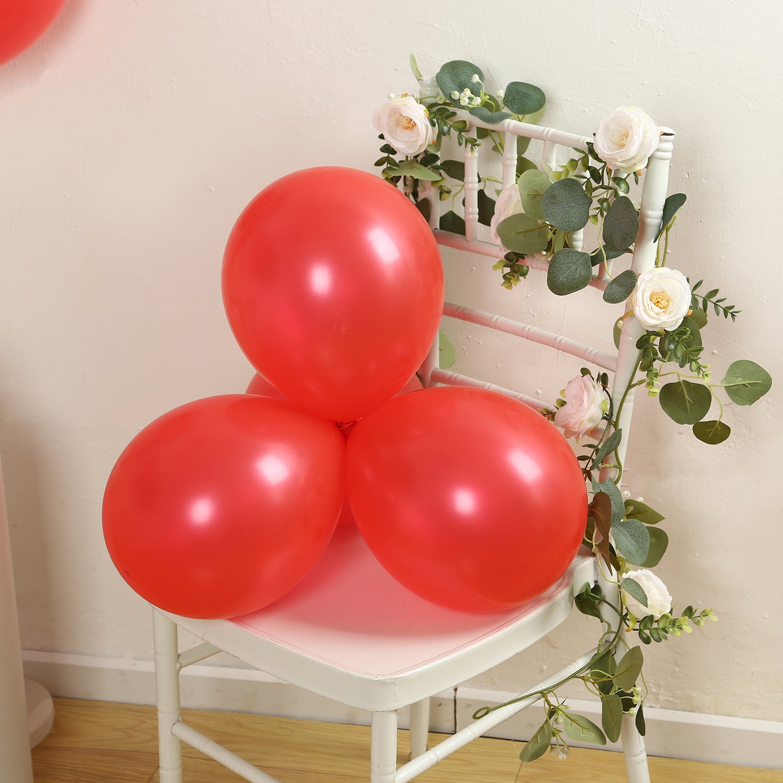 Red biodegradable balloons on a chair adorned with flowers.