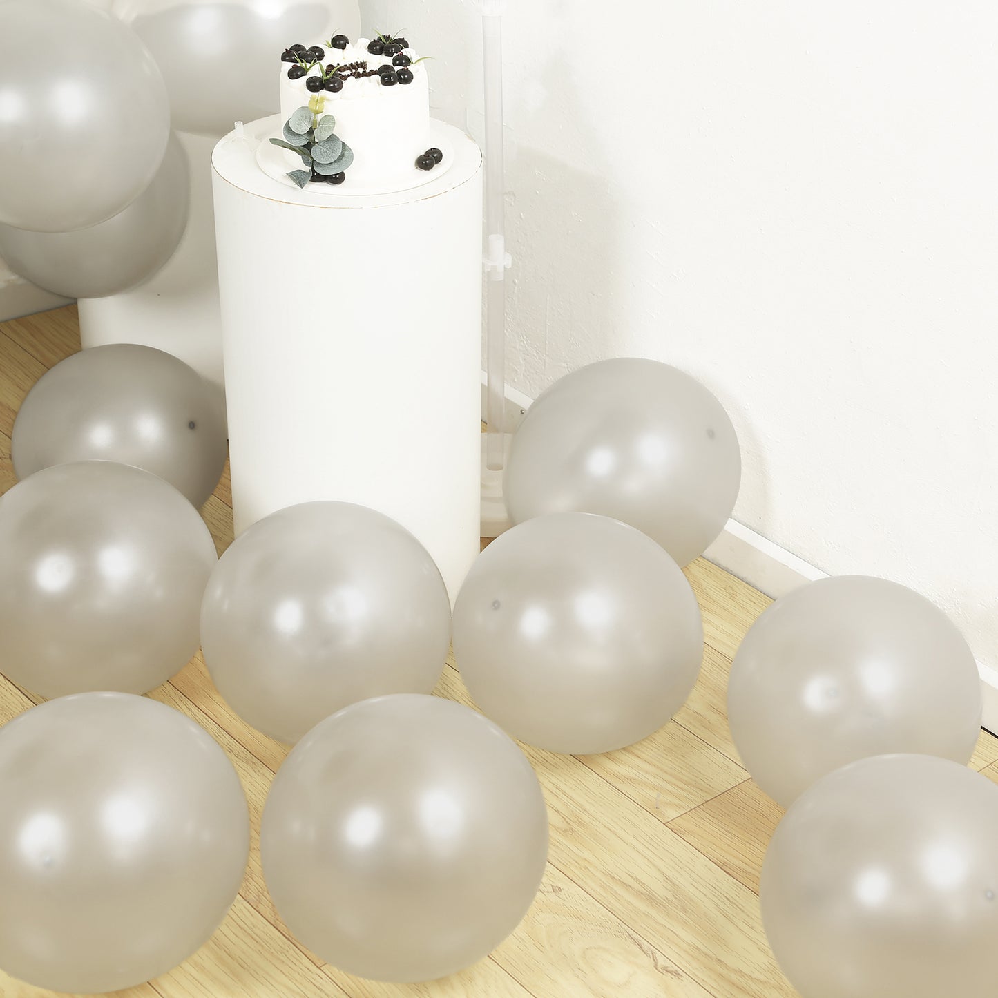 Silver biodegradable balloons scattered on a wooden floor.