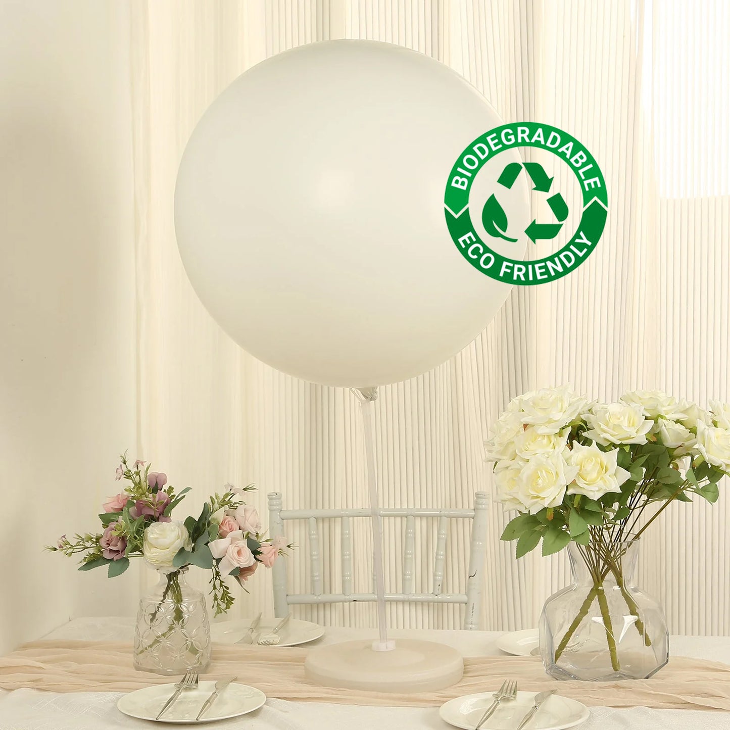 Large off white biodegradable balloon on a table with flowers and decor.