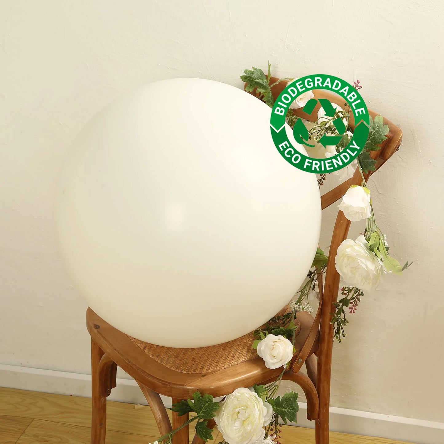 Off white biodegradable balloon on a wooden chair with flowers.