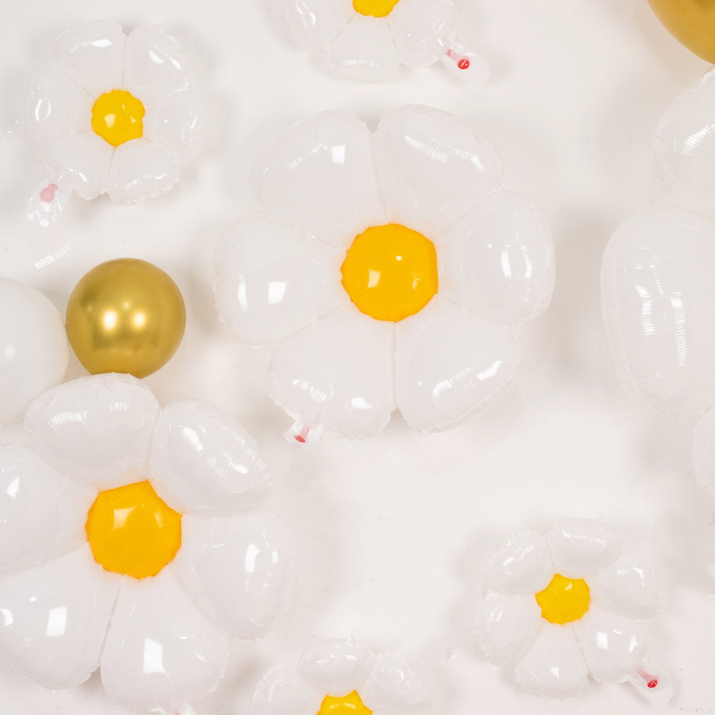 White daisy flower-shaped mylar foil balloons with yellow centers.