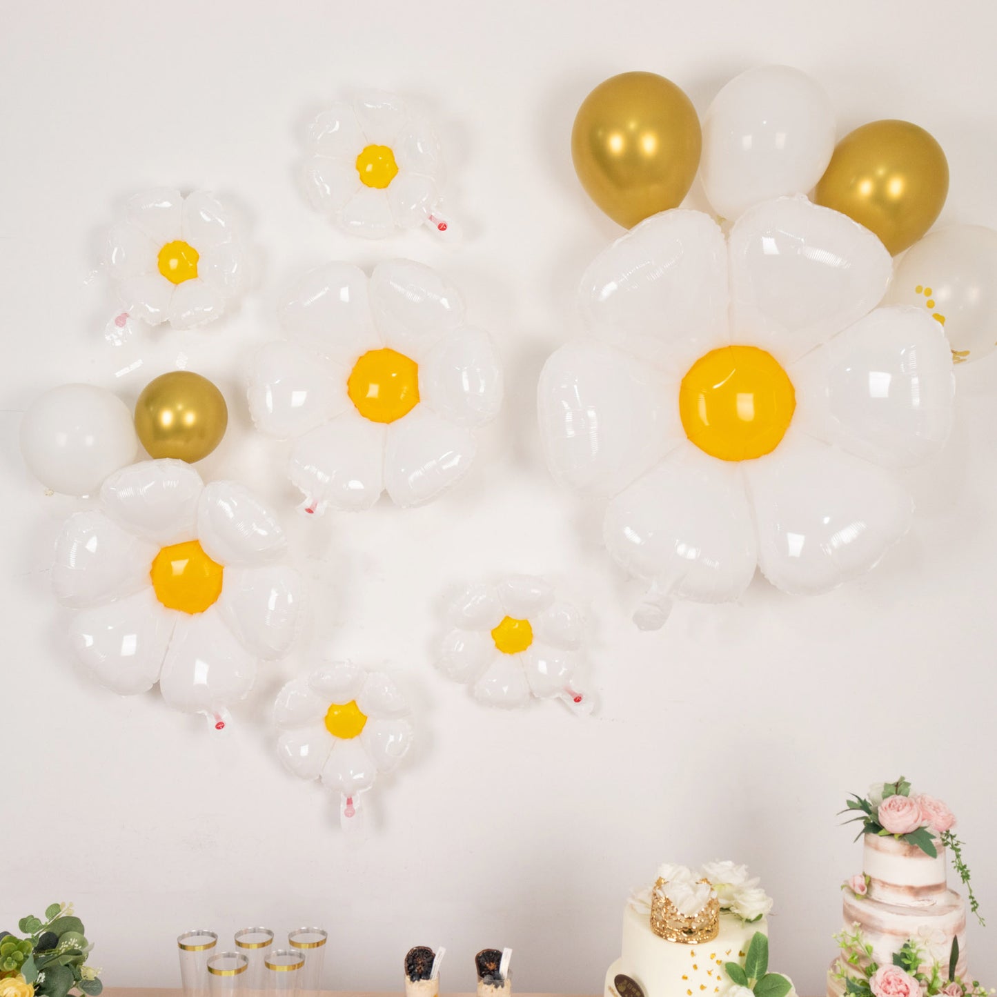 White daisy flower-shaped balloons with yellow centers for party decorations.
