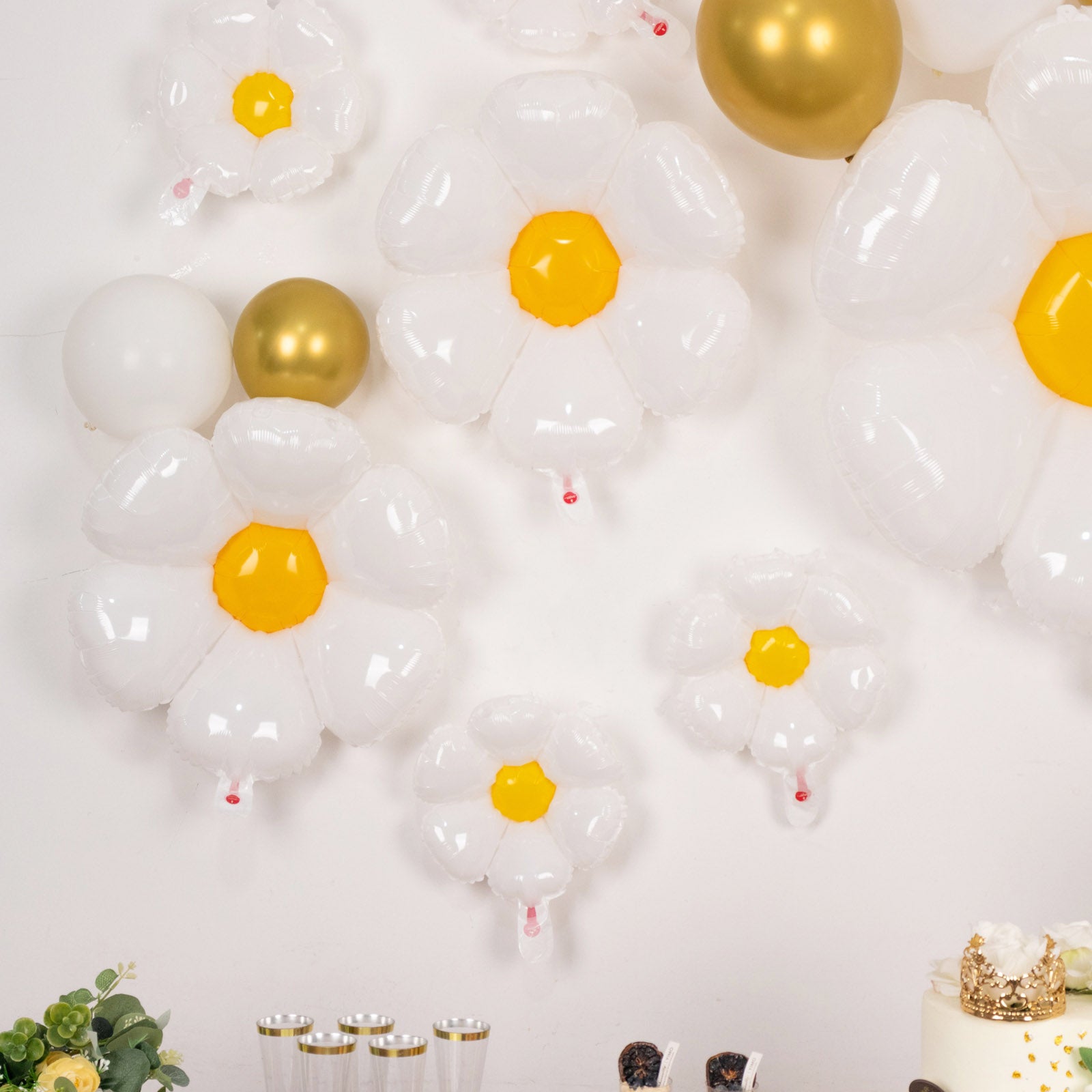 White daisy flower-shaped balloons with yellow centers, assorted sizes.