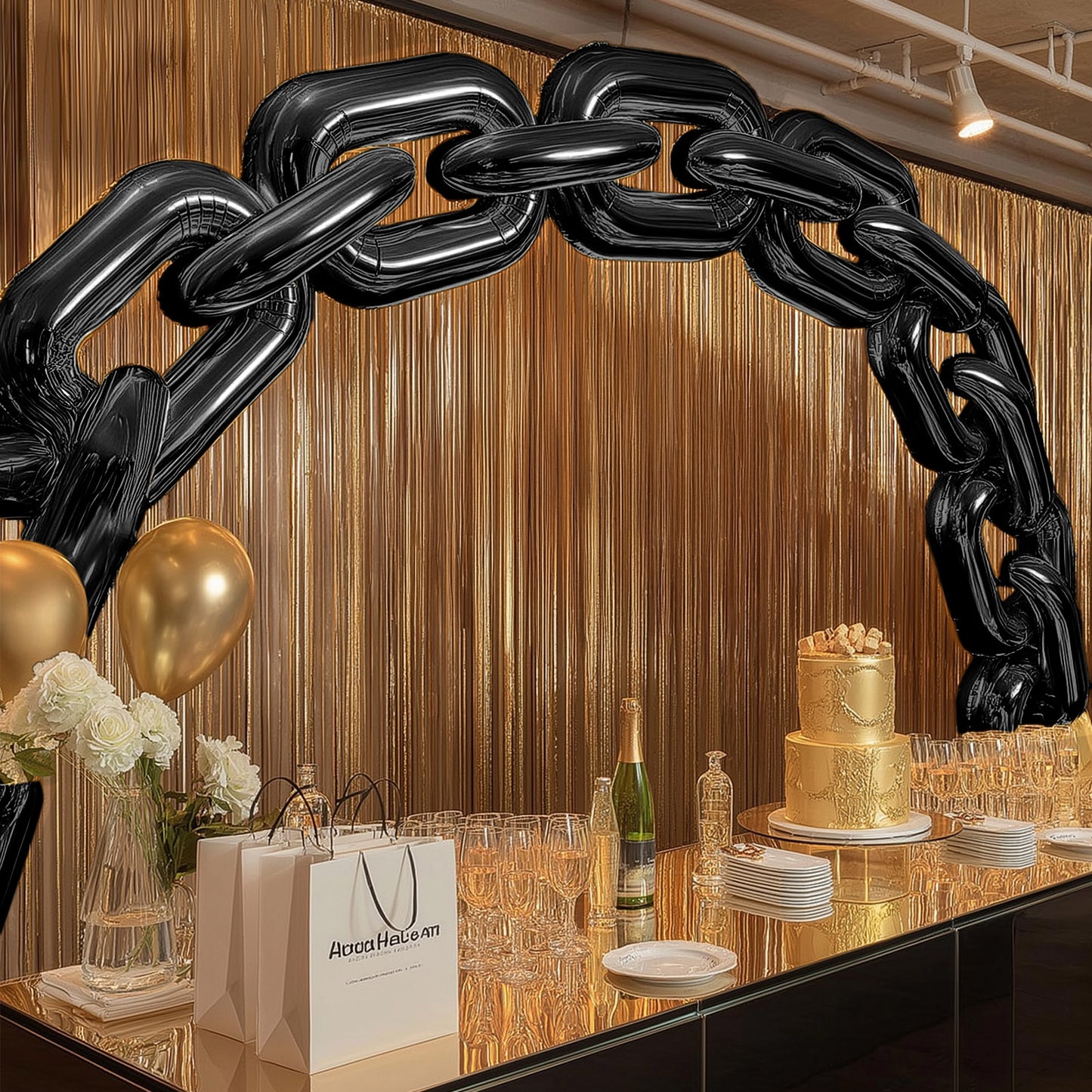 Black chain foil balloons arching over a party table with gold decor.