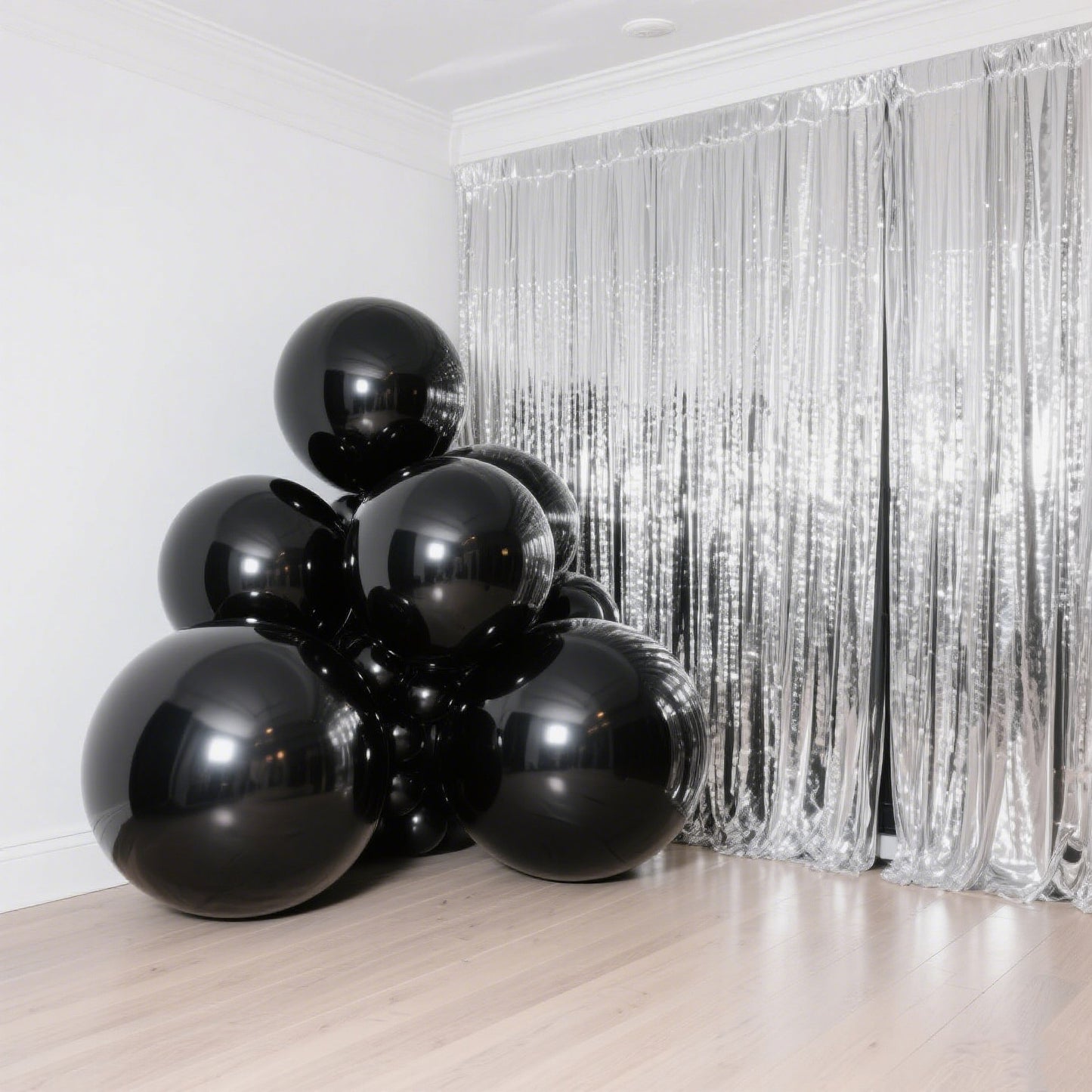 Metallic black sphere balloons stacked in a corner with shiny backdrop.