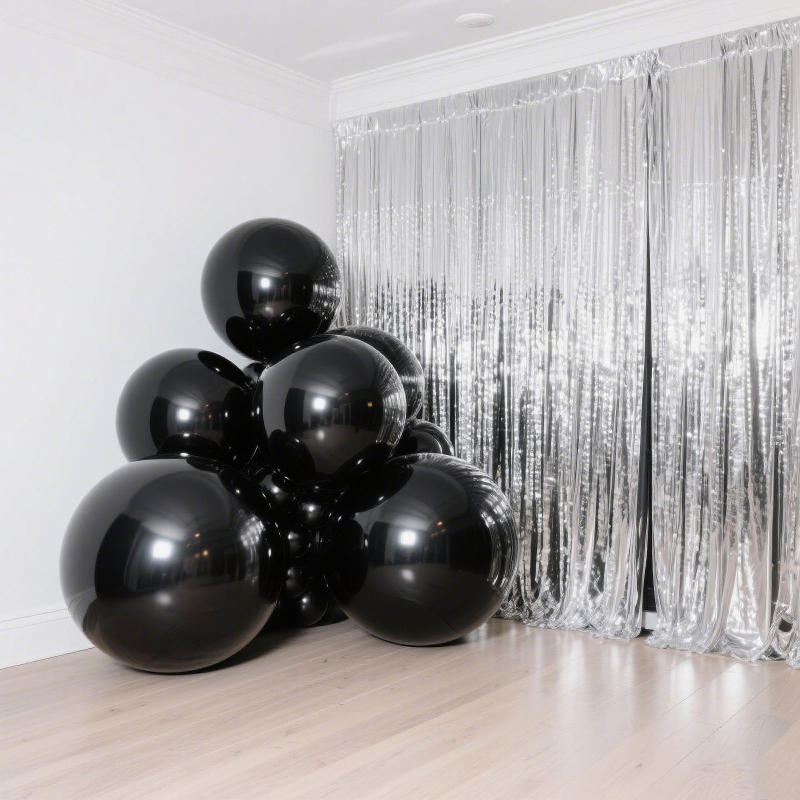 Metallic black sphere balloons stacked in a corner with shiny backdrop.