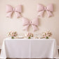 Matte blush giant decorative foil bow balloons on a party backdrop.