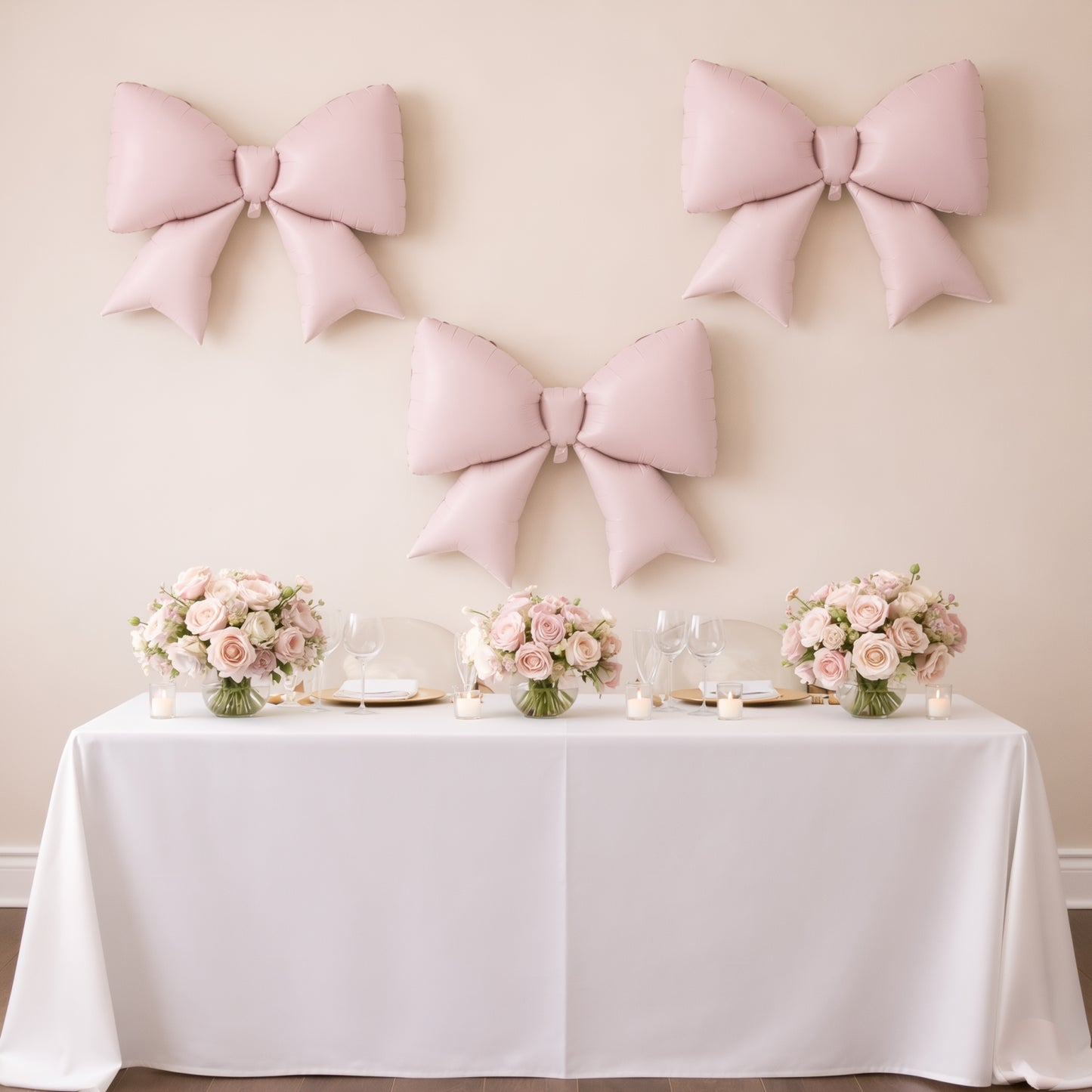 Matte blush giant decorative foil bow balloons on a party backdrop.