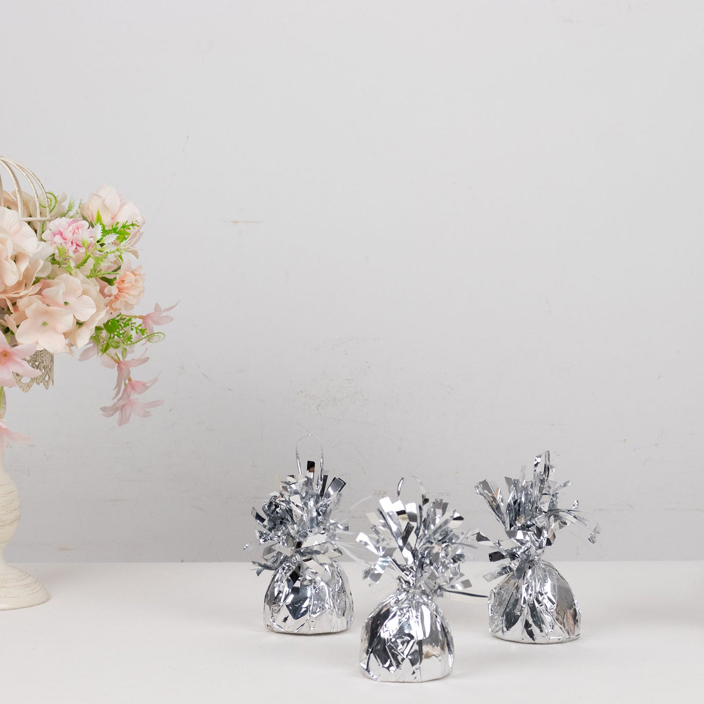 Metallic silver foil tassel top party balloon weights on a table.