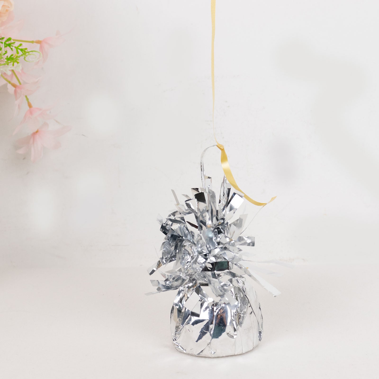 Metallic silver foil tassel top party balloon weight with yellow ribbon.