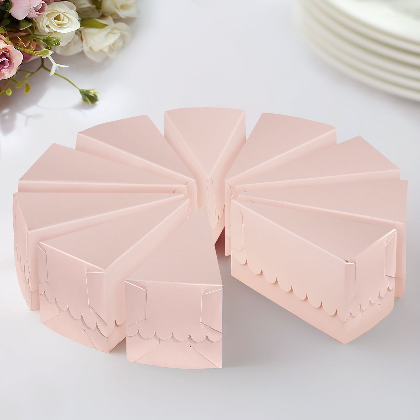 Blush triangular paper cake boxes with scalloped tops, arranged in a circle.