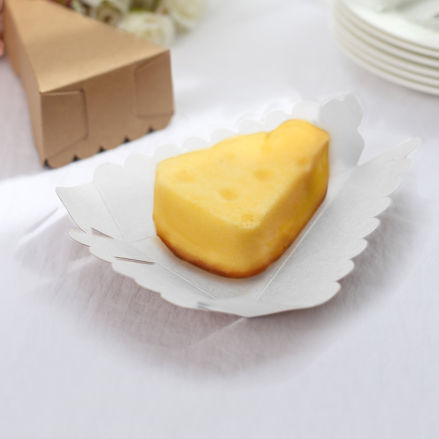 Natural brown paper cake box with a triangular shape, holding a yellow dessert.