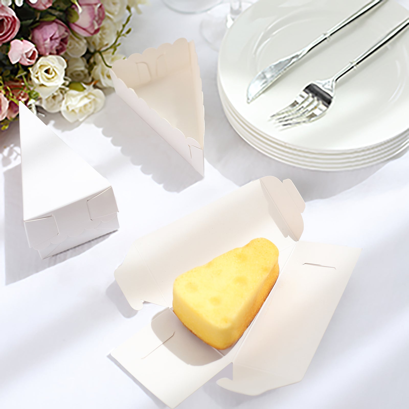 White triangular paper cake box with scalloped top and dessert inside.